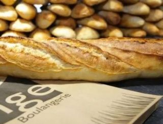 Plusieurs baguettes de pain posées sur un sac en papier dans une boulangerie