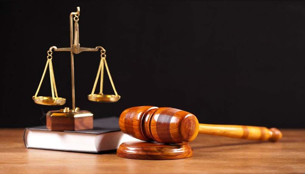 Balance de la justice posée à côté d un marteau de juge sur un livre sur une surface en bois
