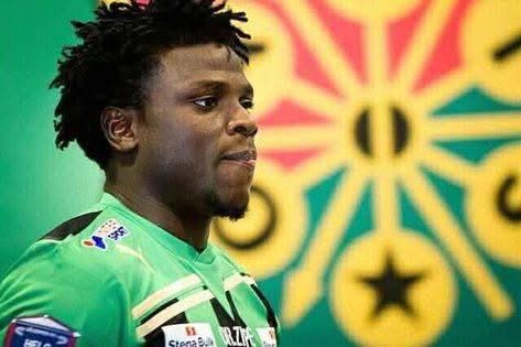 Jeune homme portant un maillot de football vert devant un drapeau coloré flou en arrière-plan