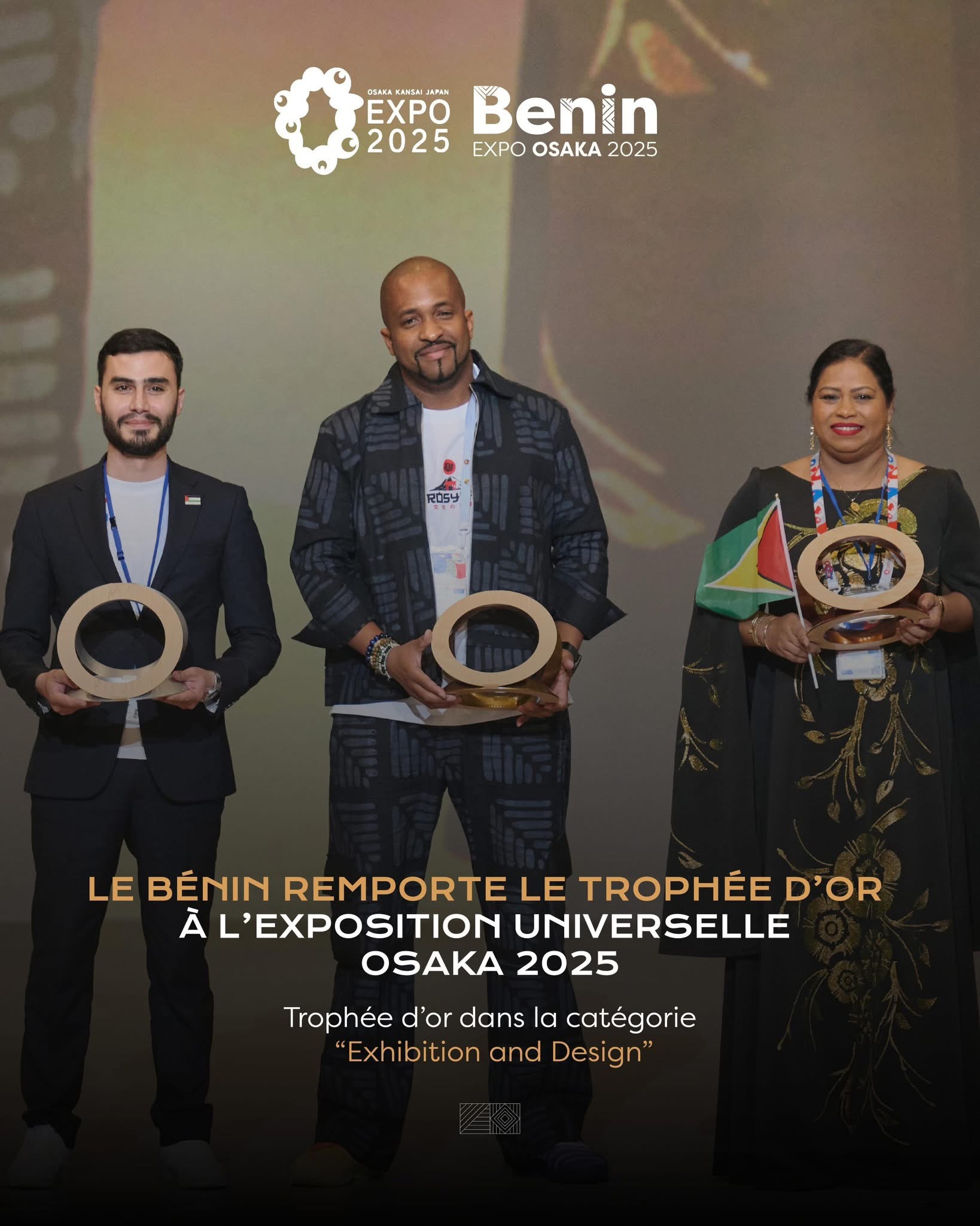 Trois personnes debout, souriantes, tenant chacune un trophée rond devant un fond avec le logo Expo 2025 et le mot Benin
