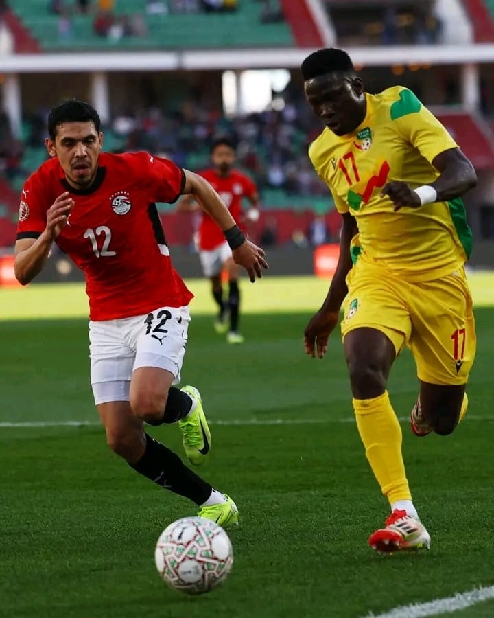 Deux joueurs de football en course vers le ballon sur un terrain durant un match intense