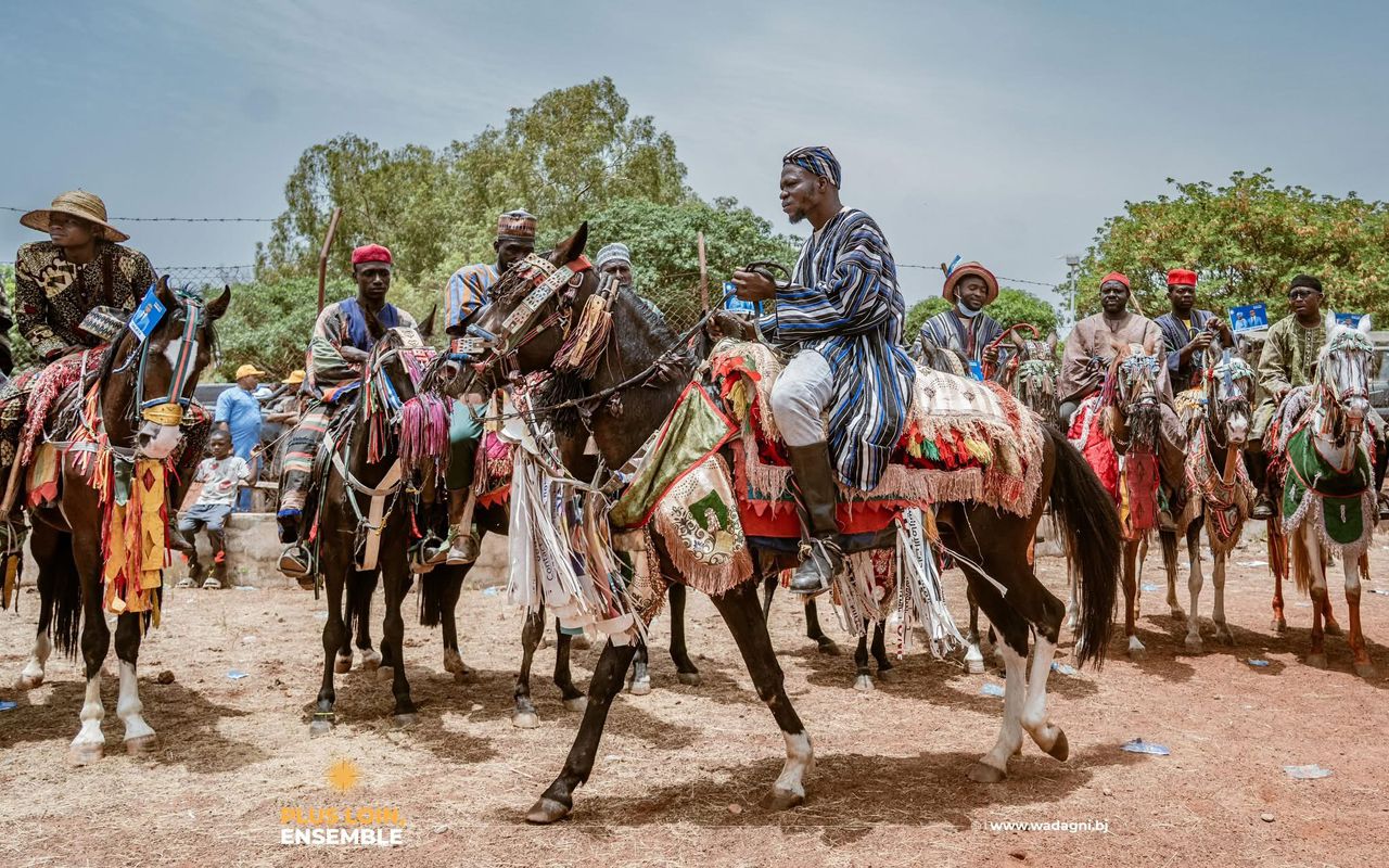 Hommes en tenue traditionnelle sur des chevaux ornés de tissus colorés lors d’un rassemblement en plein air