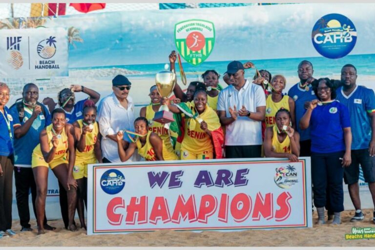 Une équipe féminine de beach handball en tenues jaunes célèbre la victoire avec un trophée et une bannière « WE ARE CHAMPIONS