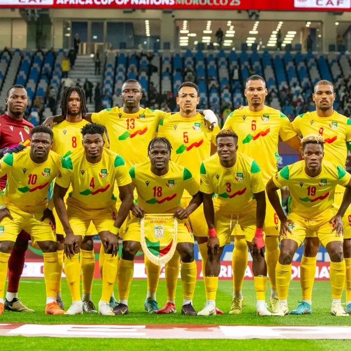 Onze joueurs de football en maillots jaunes posent ensemble sur un terrain de stade avant un match