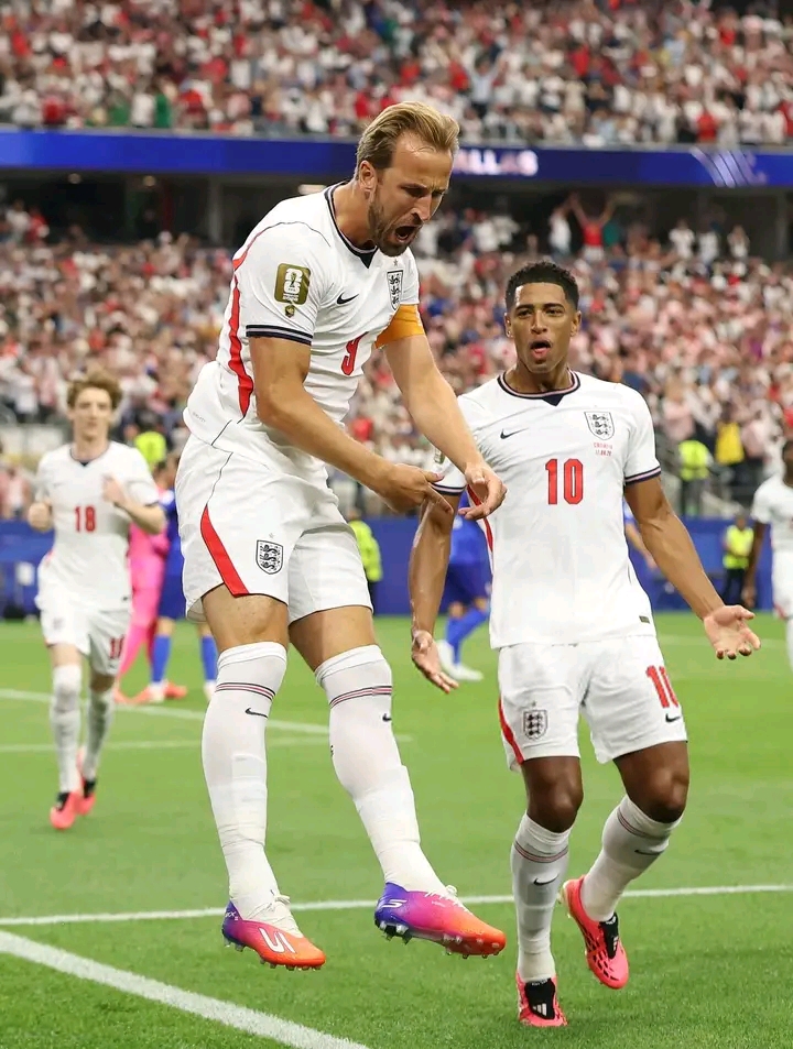 Deux footballeurs en tenue blanche célèbrent un but sur un terrain devant un public nombreux en tribunes