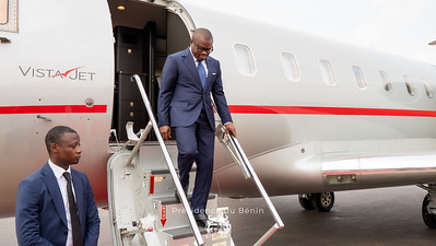 Un homme en costume descend les marches d’un avion privé blanc marqué VistaJet accompagné d’un autre homme en costume.
