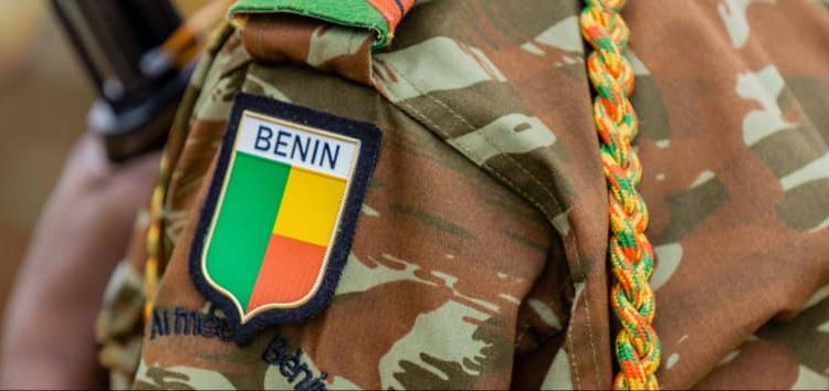 Épaule d’un uniforme militaire camouflage avec un écusson aux couleurs d’un pays africain et un cordon tressé multicolore