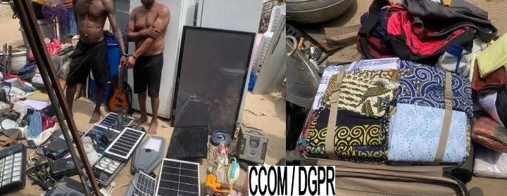 Deux hommes menottés entourés de divers objets électroniques et vêtements étalés au sol