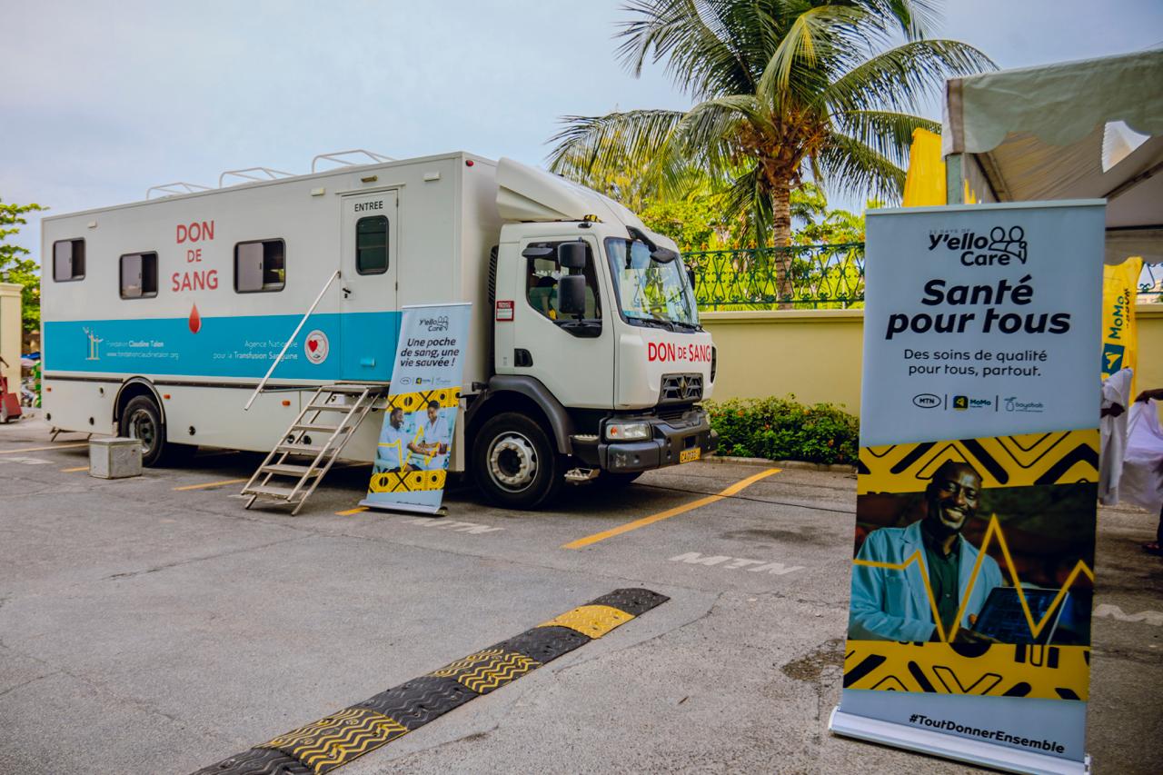 Camion aménagé pour don de sang stationné près de deux kakemono promotionnels d’une campagne santé