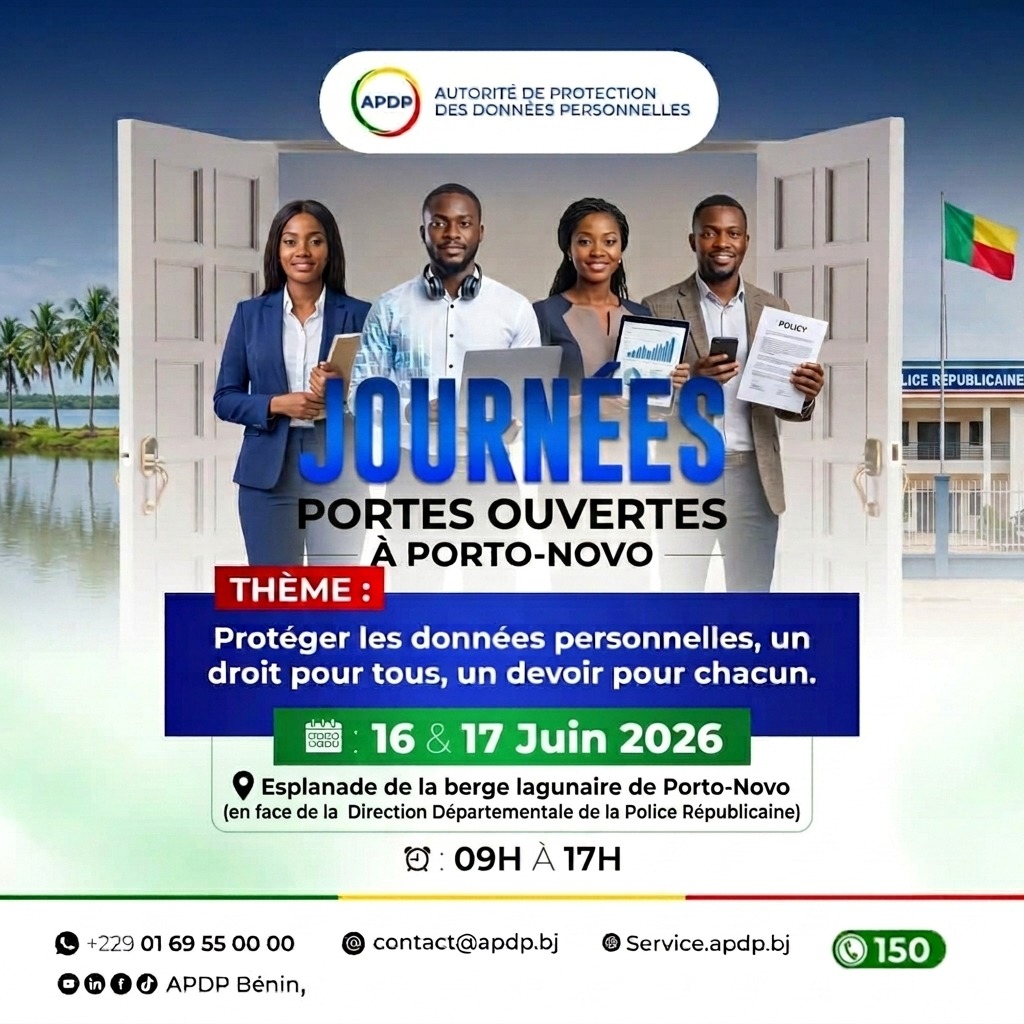 Quatre personnes debout souriant, chacune tenant un appareil ou document, sur fond d’une porte ouverte et d’un drapeau national